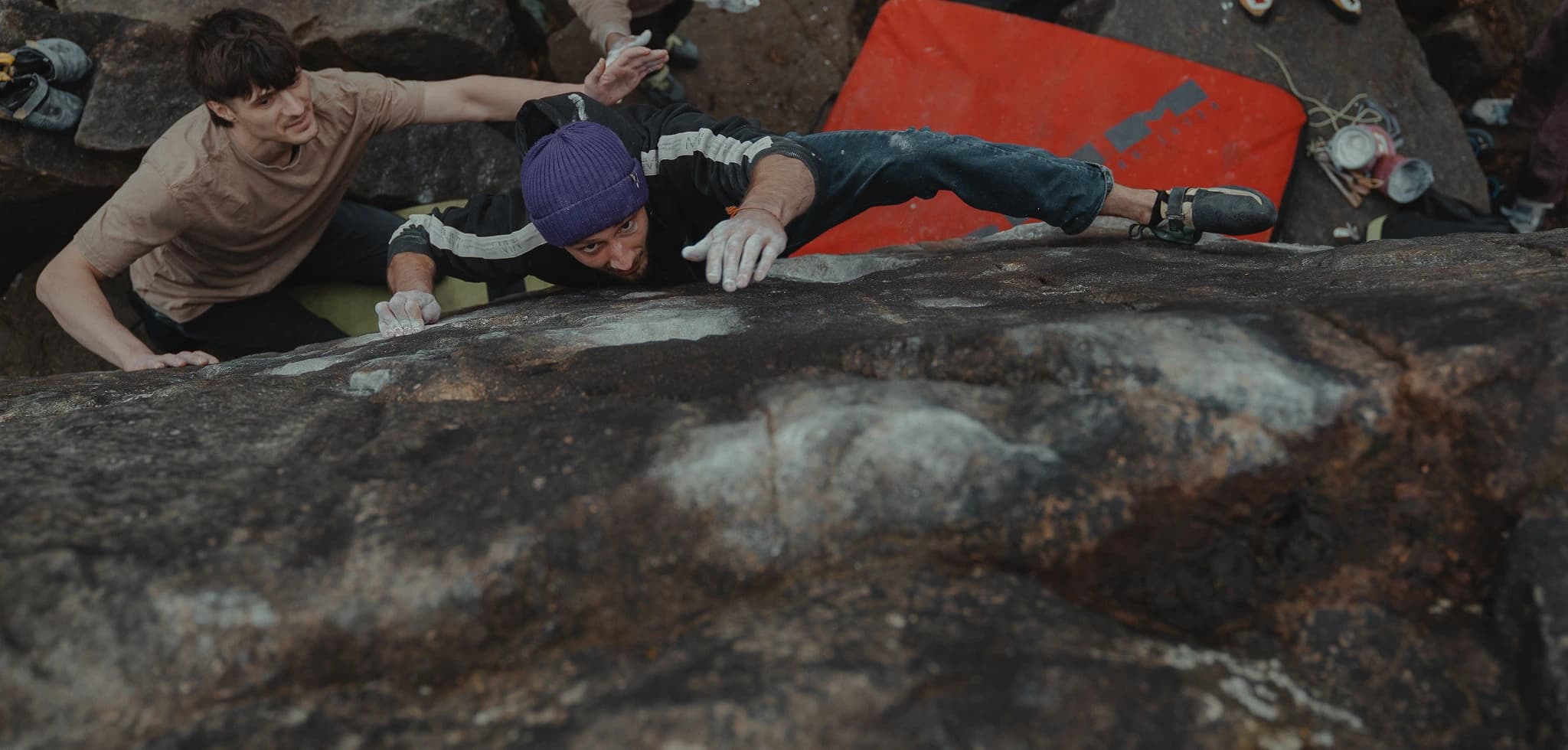 Climber reaching the top of a boulder during an outdoor session